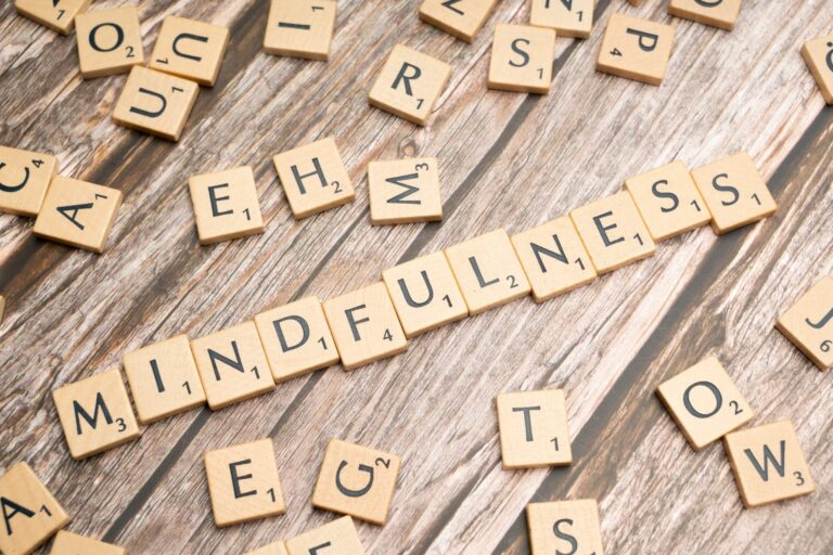 Wooden letter tiles spelling 'mindfulness' on a rustic wood background.