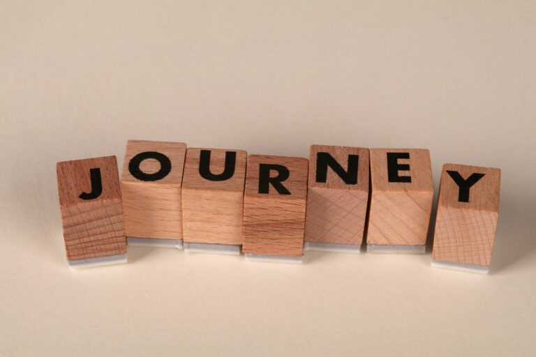 Wooden blocks arranged to spell 'Journey' on a table, symbolizing adventure or progress.